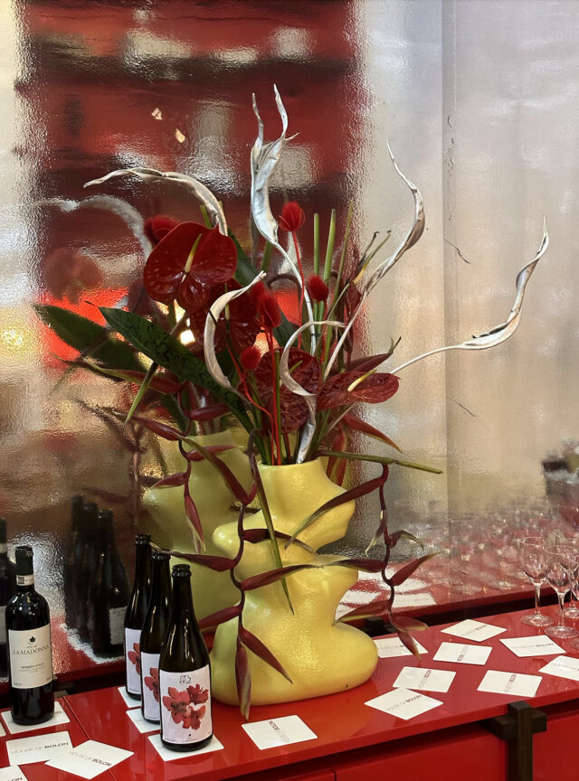 a vase with flowers and wine bottles on a table