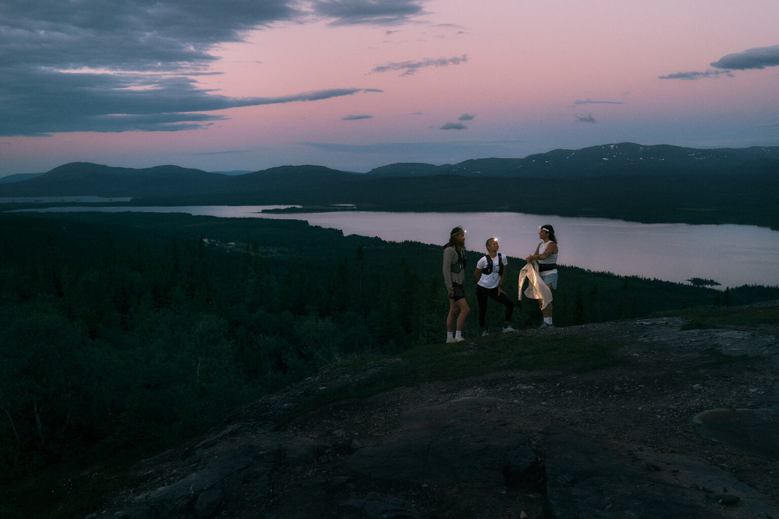 a group of people standing on a hill with a lake in the background