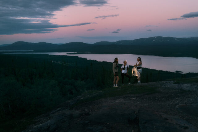 a group of people standing on a hill with a lake in the background