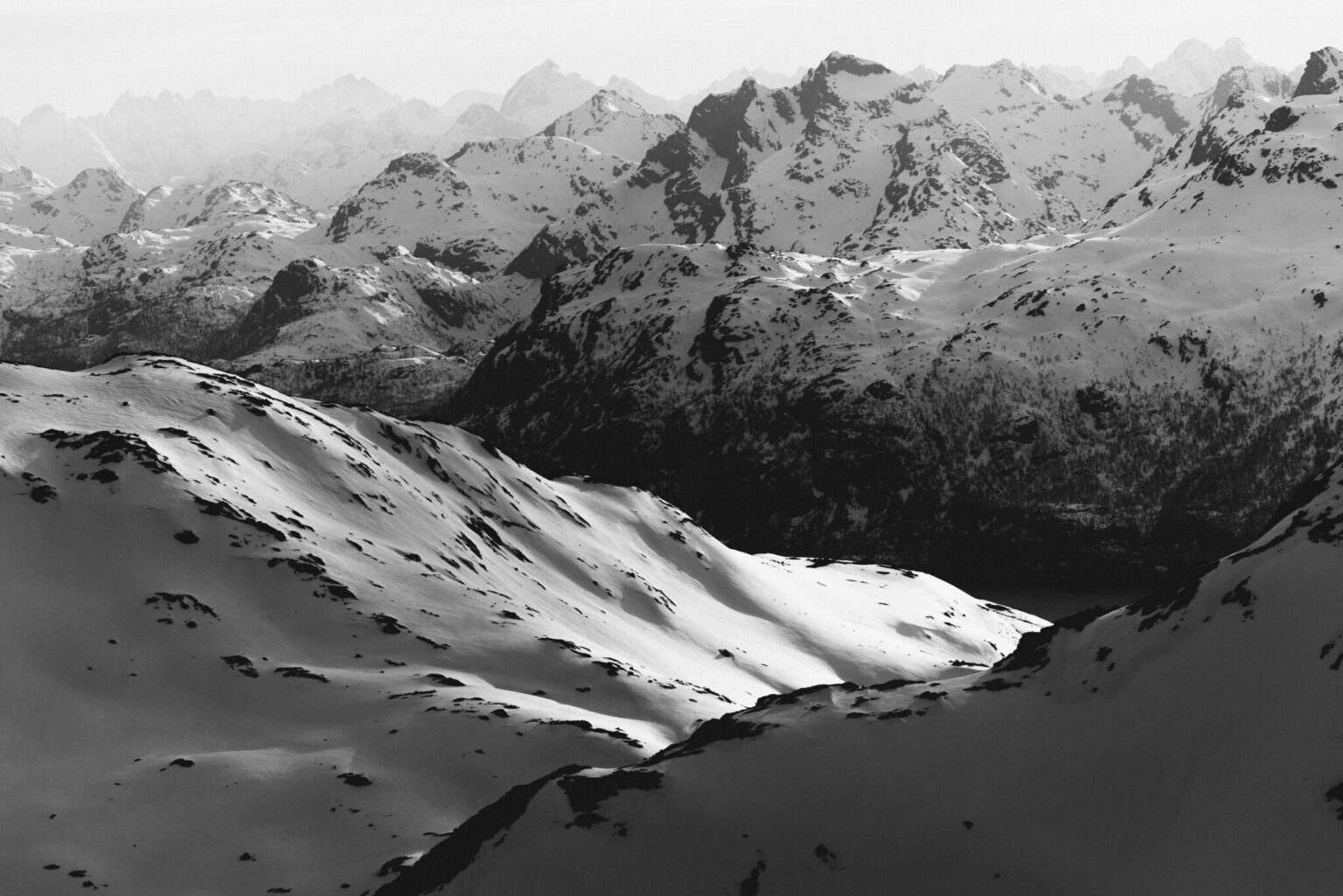 a snowy mountain range with a lake in the background