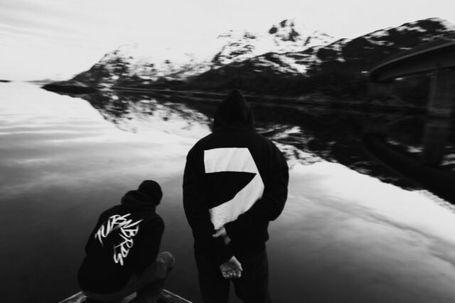 two people standing on a dock by a body of water