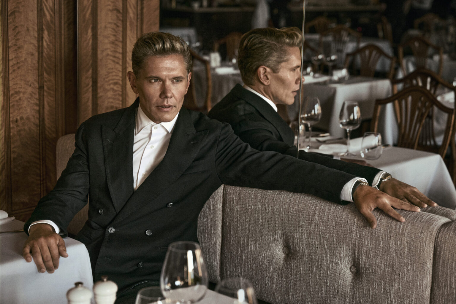 a man in a suit leaning on a booth