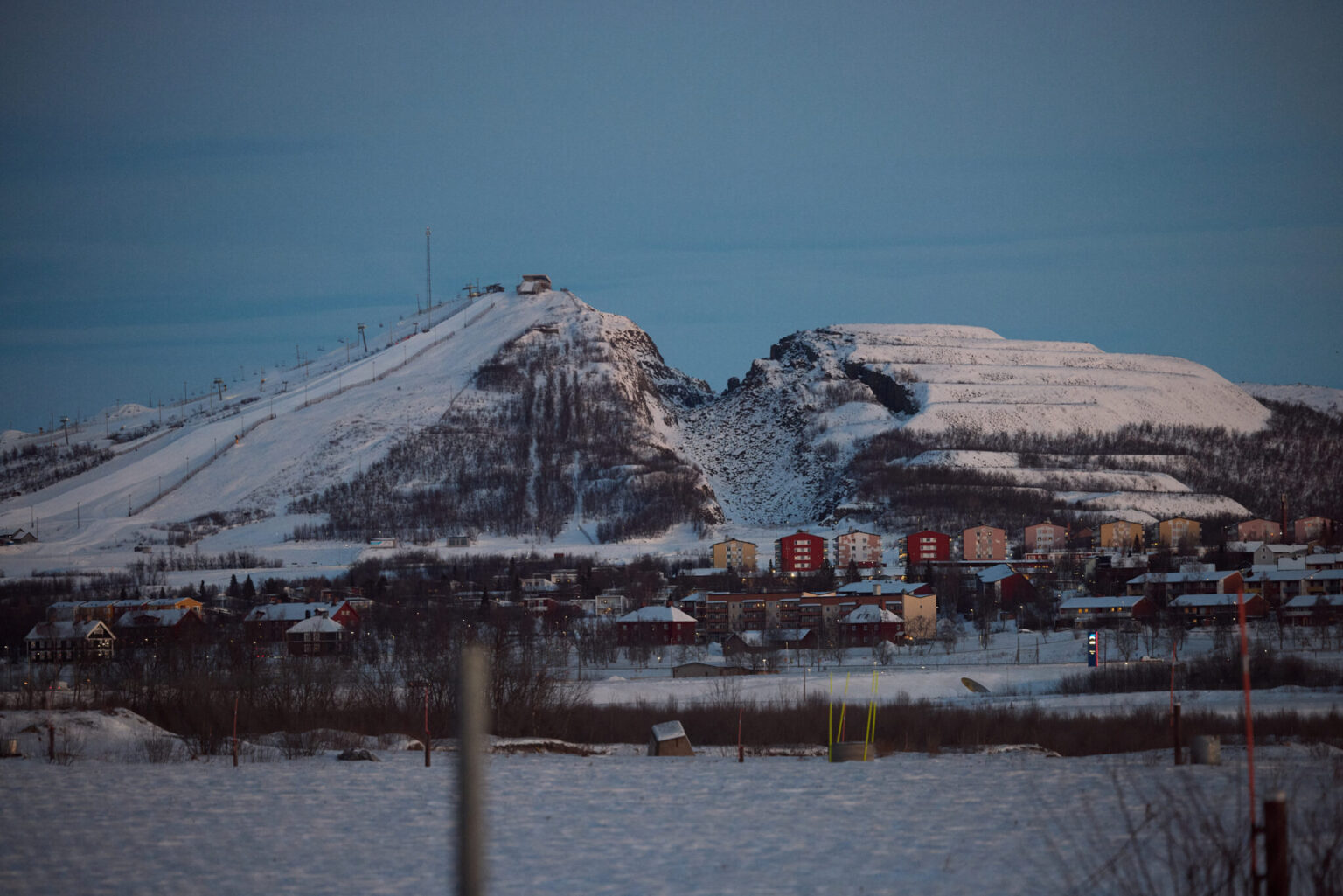 a snowy mountain with buildings and a ski lift
