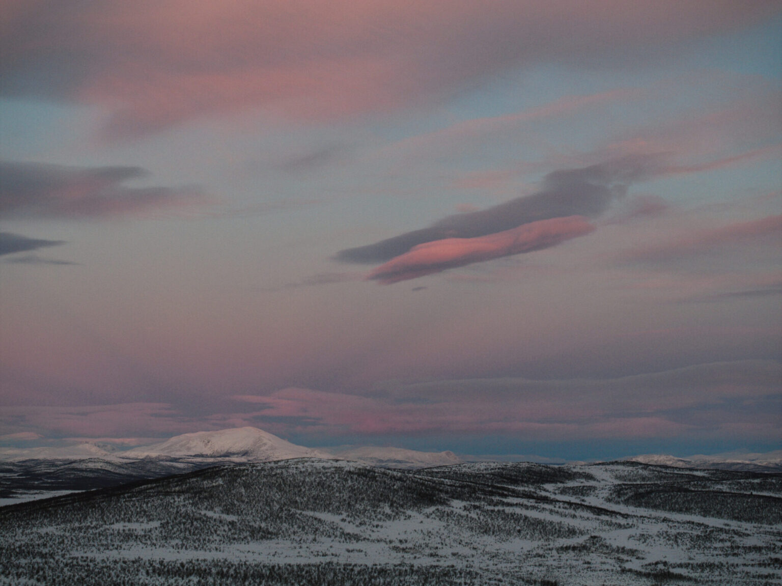 a snowy mountains with a pink sky
