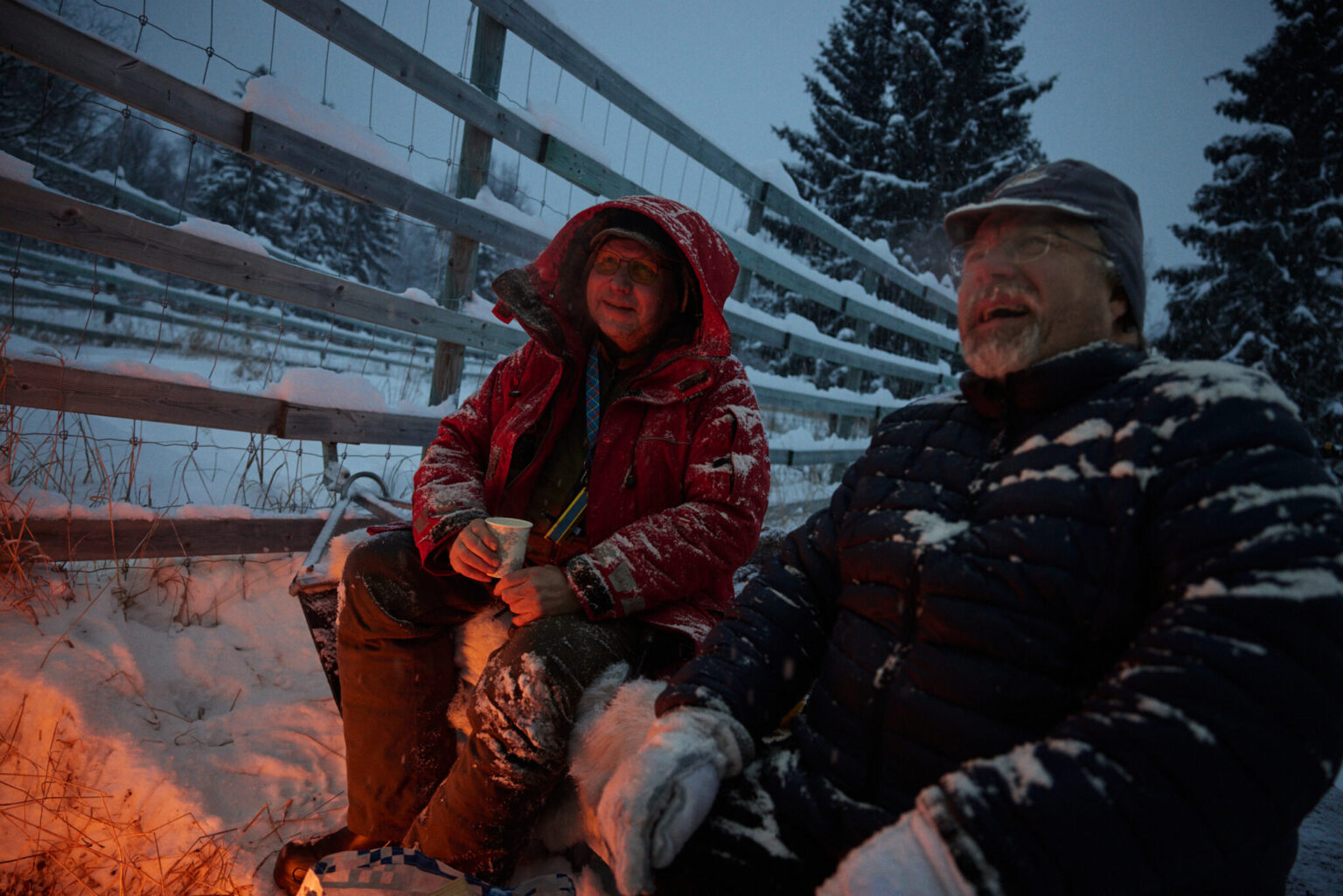 a couple sitting on a bench in the snow