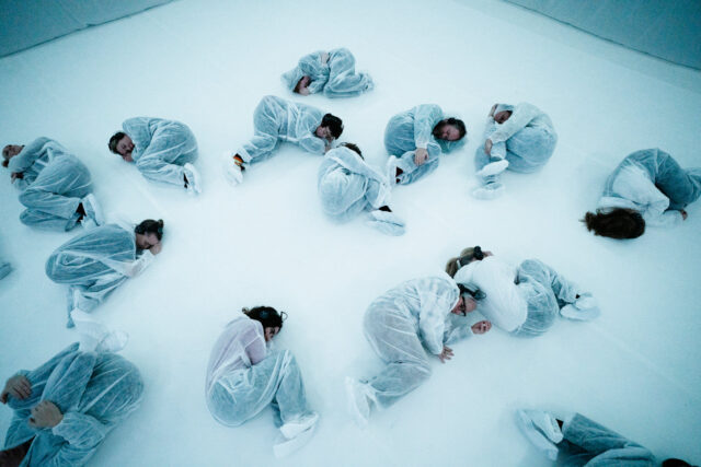 a group of people in white outfits lying on the floor