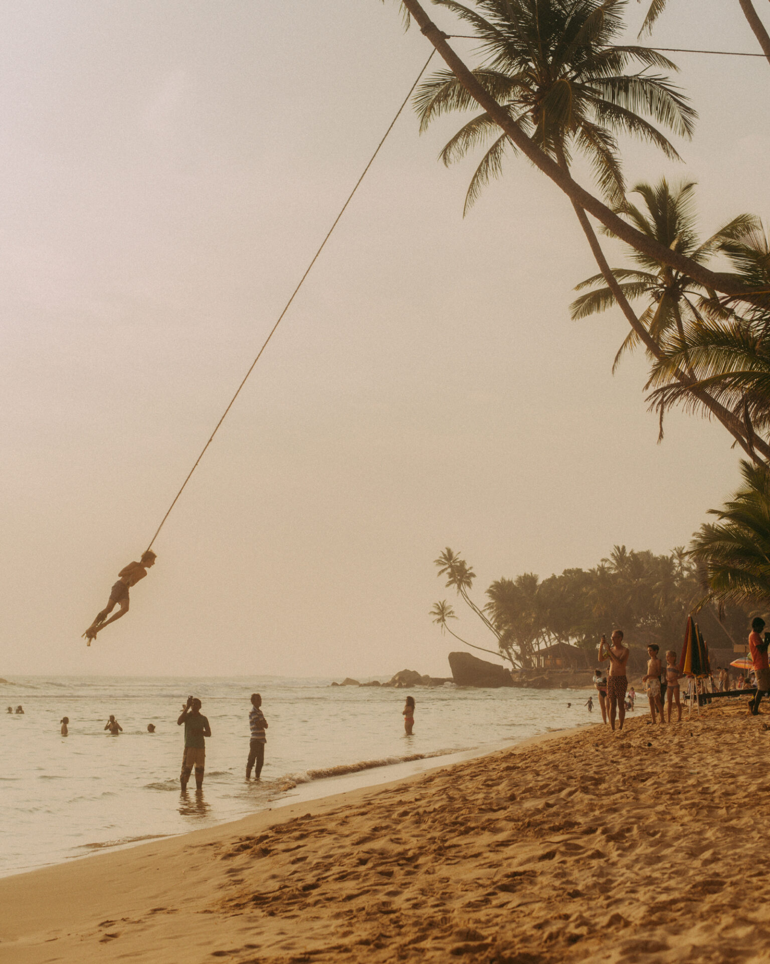 a person swinging on a rope at a beach