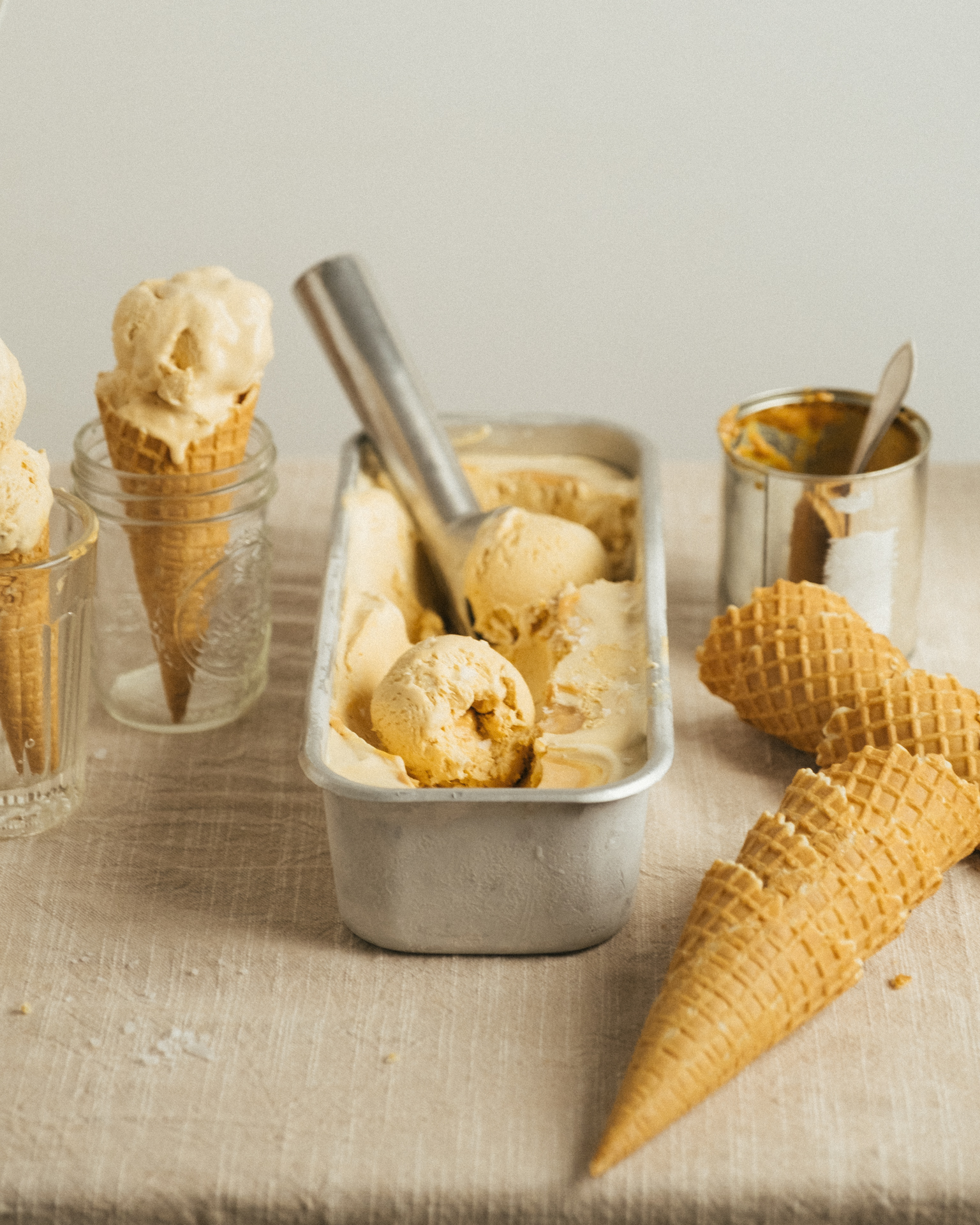 a tray of ice cream in a container with cones and a spoon