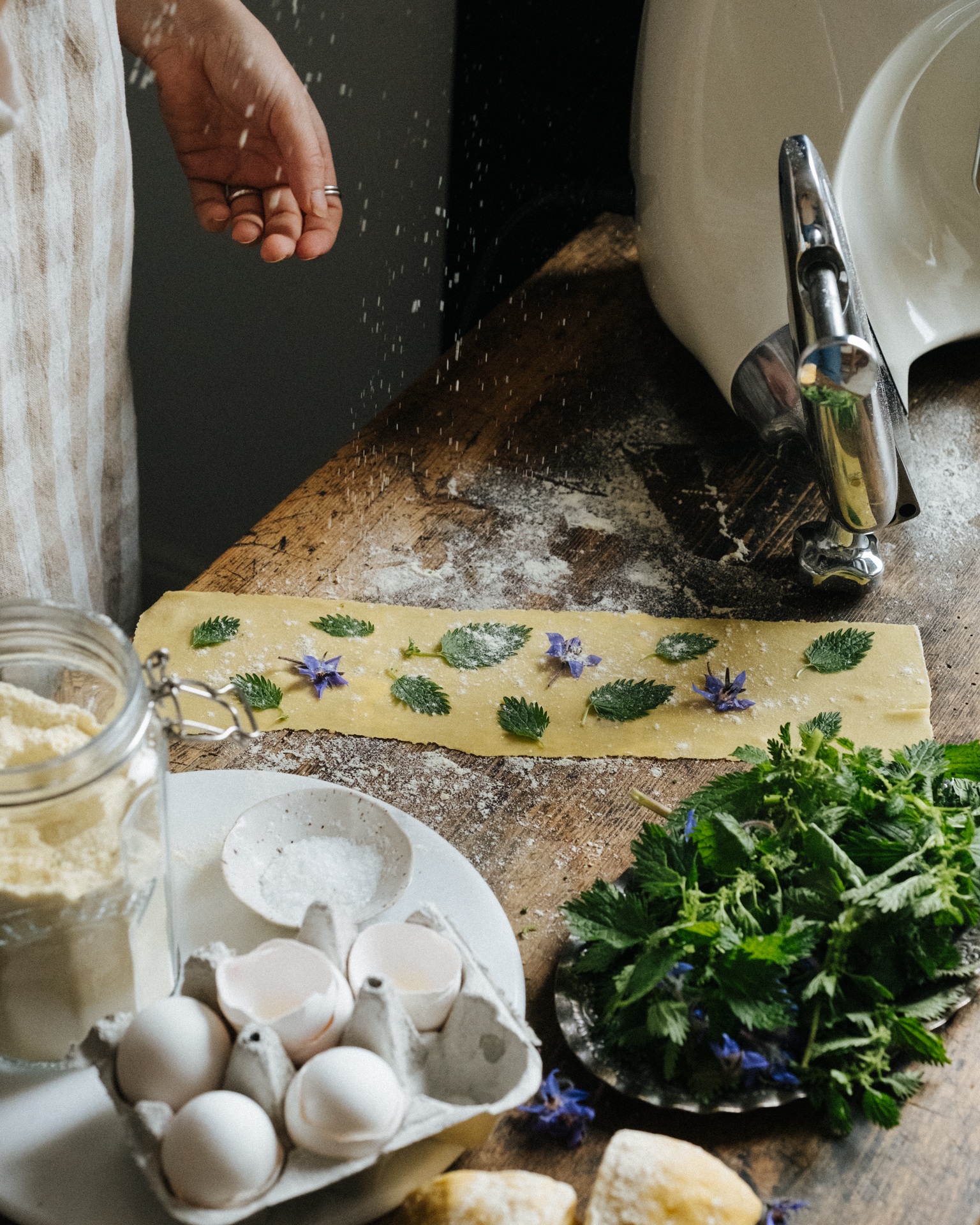 a person sprinkling flour on a table with food