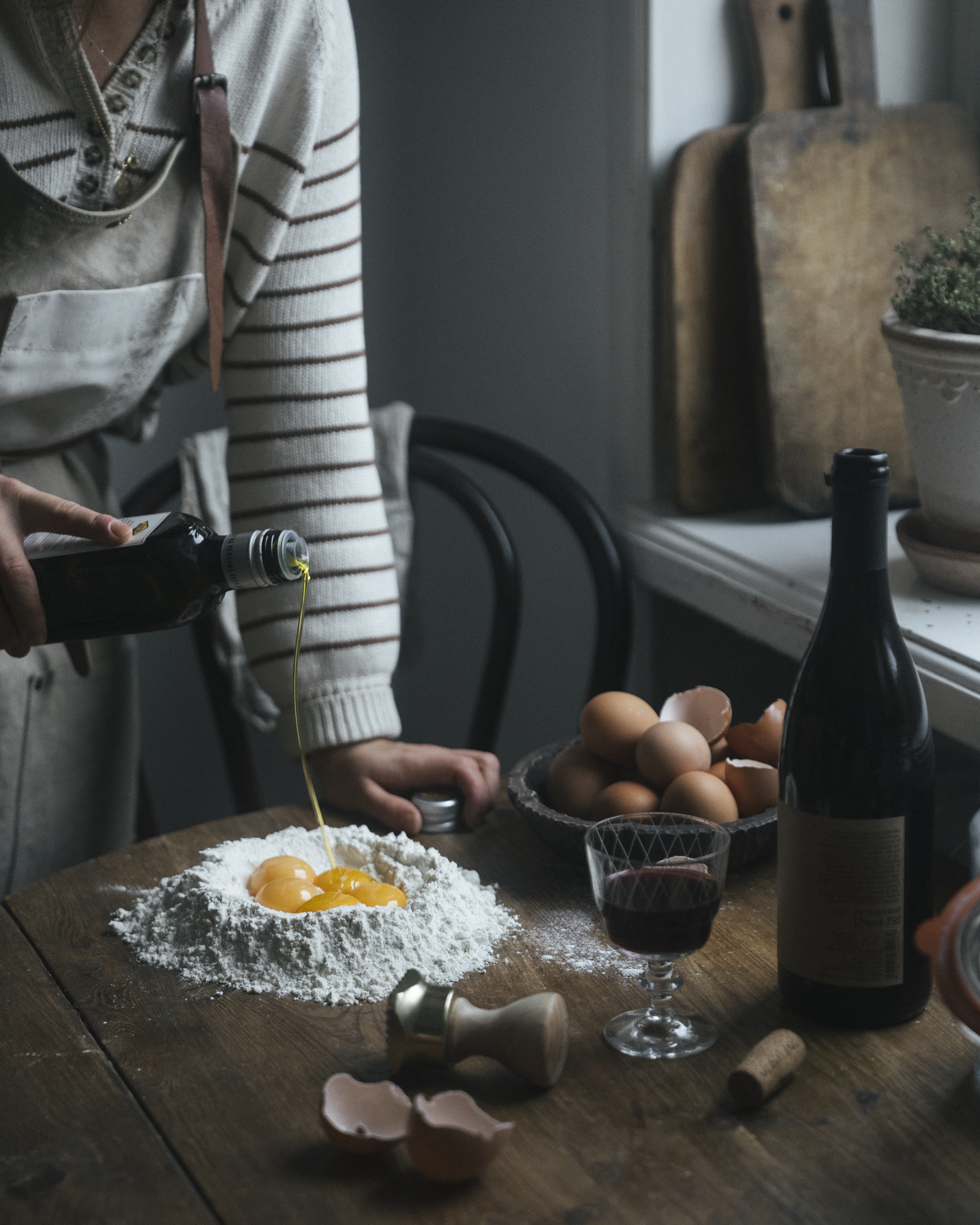 a person pouring eggs into flour on a table
