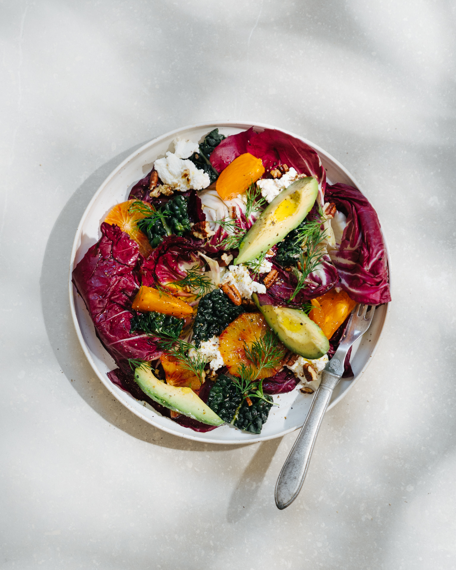 a plate of salad with avocado and oranges