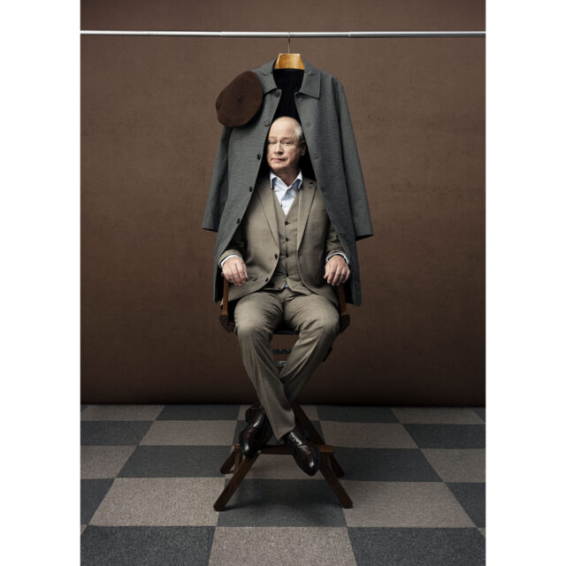 a man sitting in a chair with a coat on a swinger