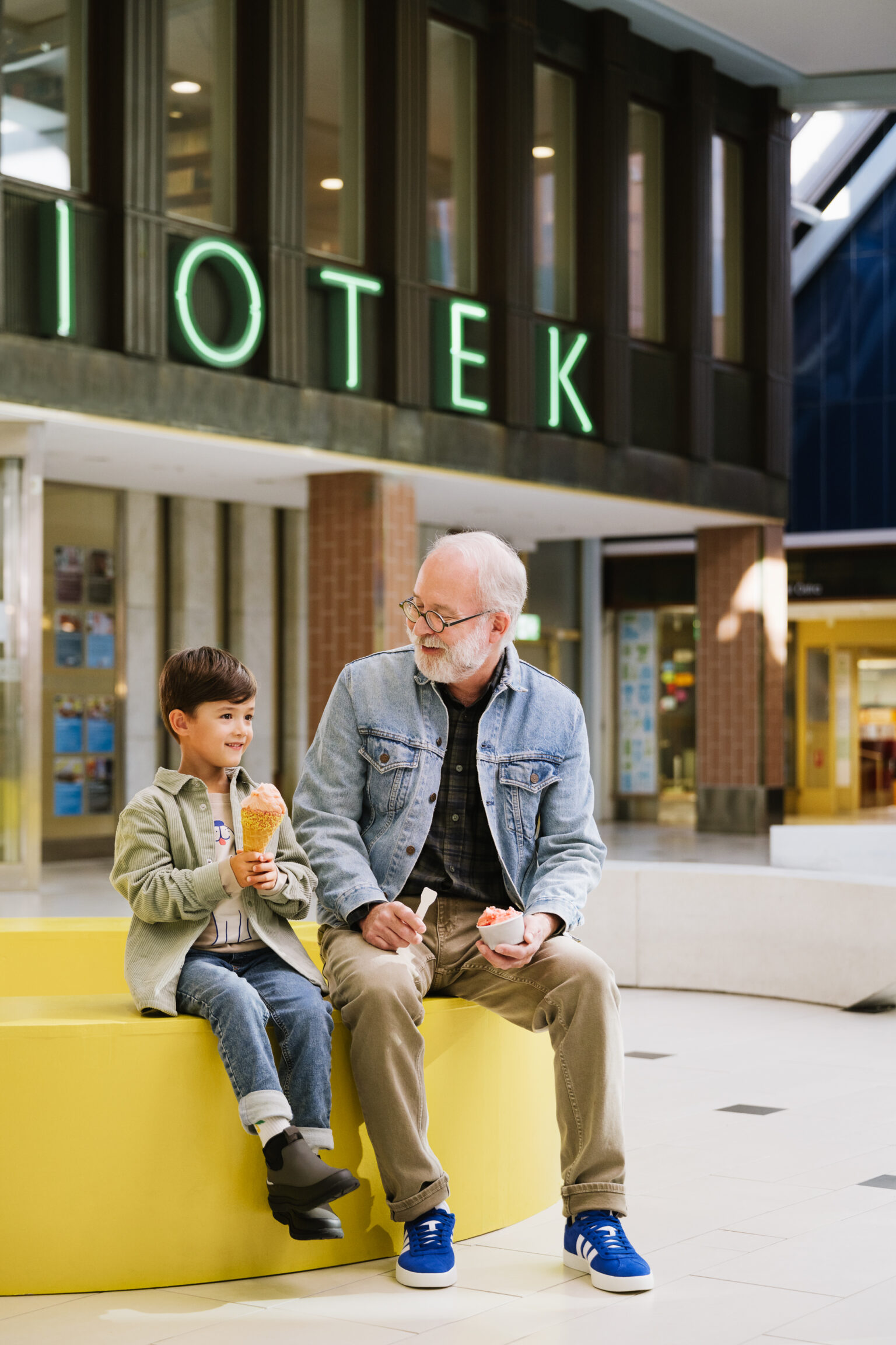 a man and boy sitting on a bench eating ice cream