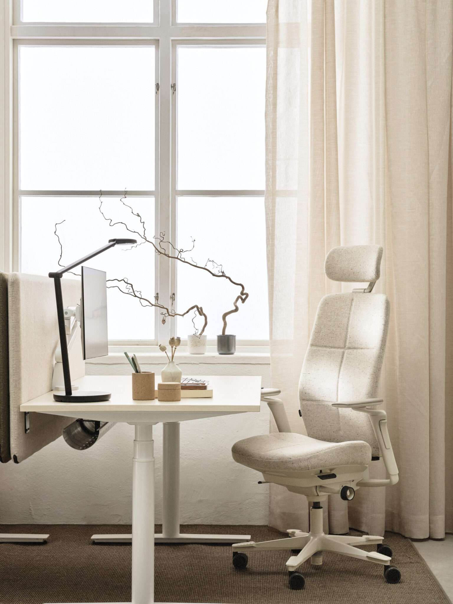 a desk with a computer and a chair in front of a window