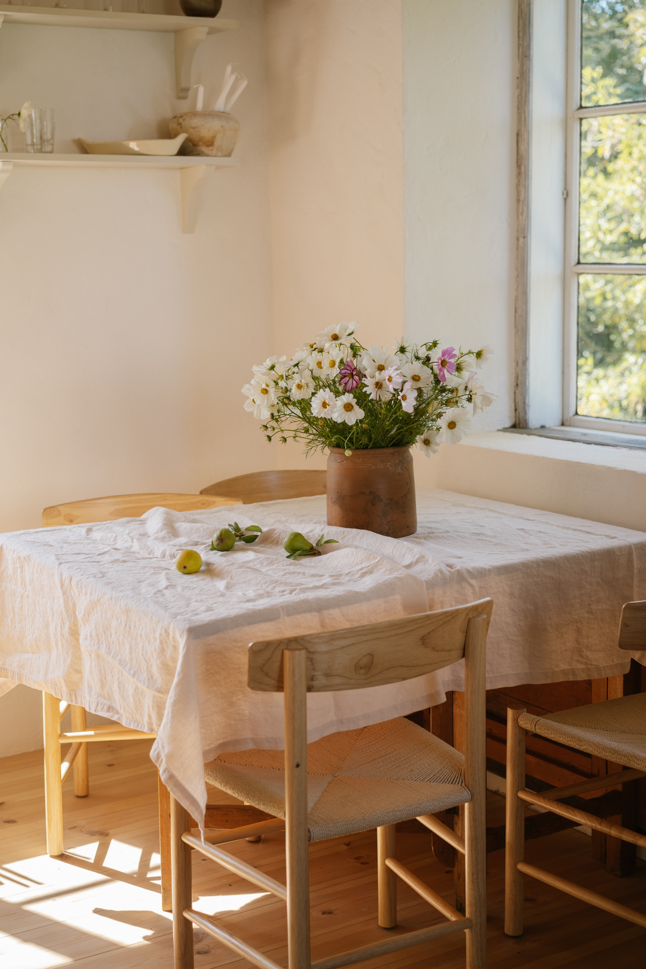 a vase of flowers on a table with a tablecloth and chairs
