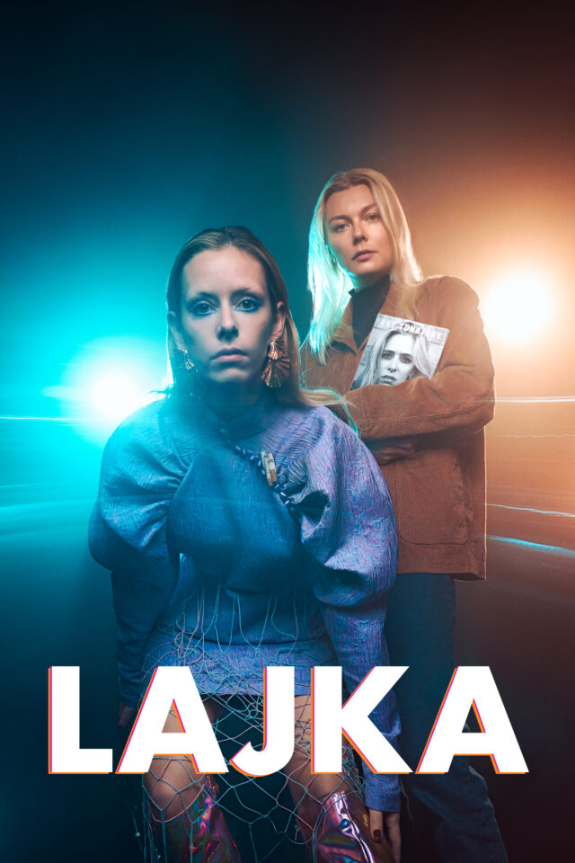 two women standing in front of a blue and yellow light