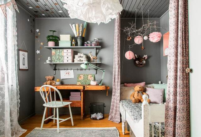 A child's room with a desk, bed, and decorative elements.