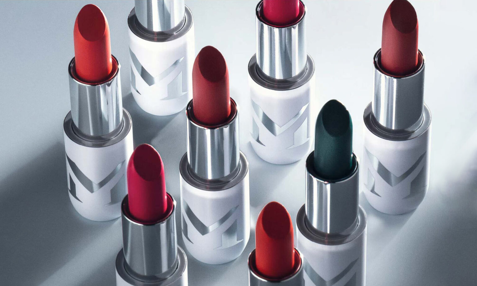 A collection of lipsticks in various shades of red and green with silver metallic cases.