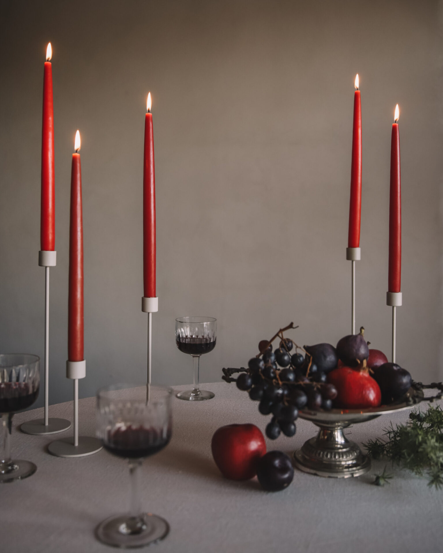 Red candles and fruit on a table.