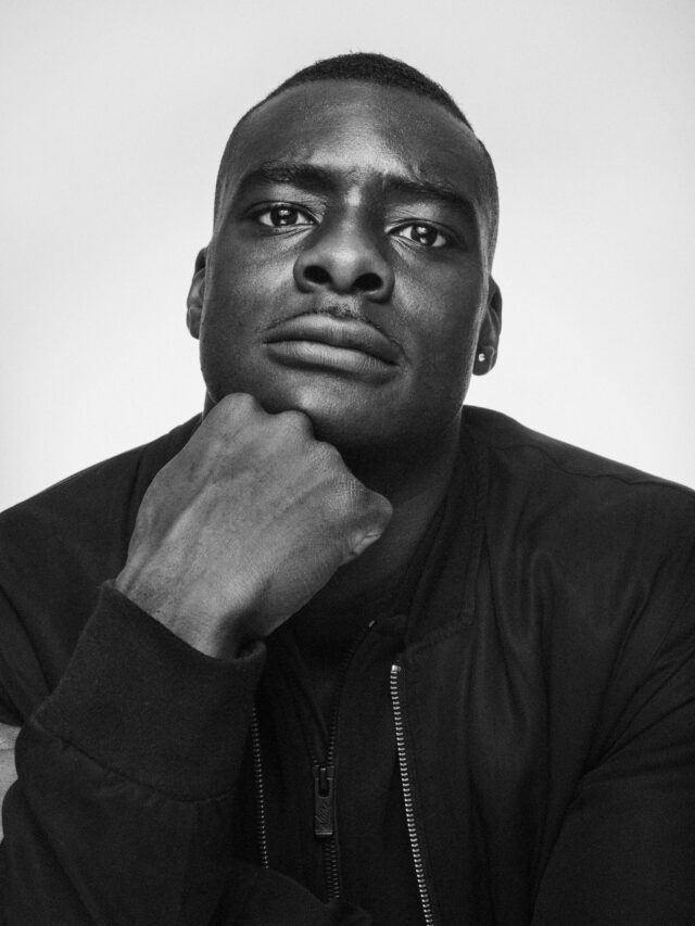 Black and white portrait of a Black man with his chin resting on his fist.